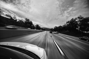 Black and white photo of an electric car driving down a motorway