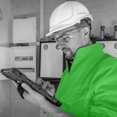 Engineer stood in front of fuse box checking tablet as Jumptech's Atom app allows for photos to be uploaded during site surveys