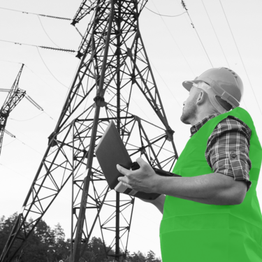 Engineer in the field holding a laptop while looking at a pylon